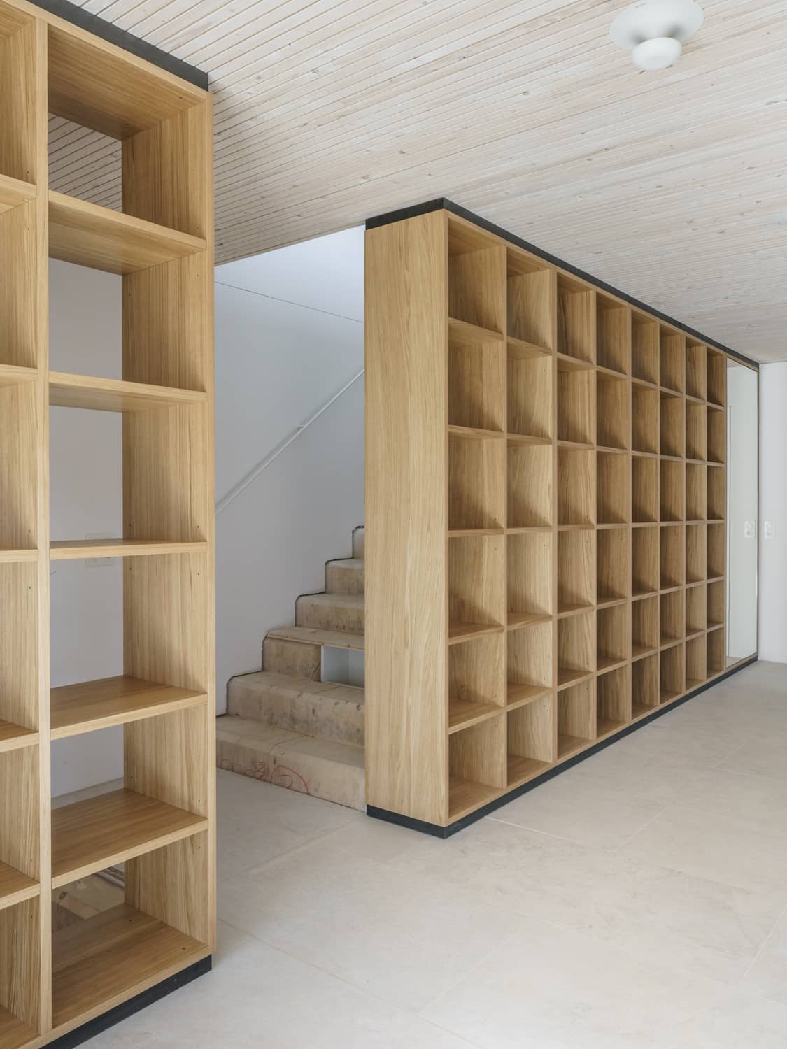 Hinter einem eingebauten Regal f&uuml;hrt eine Treppe in den oberen Stock
